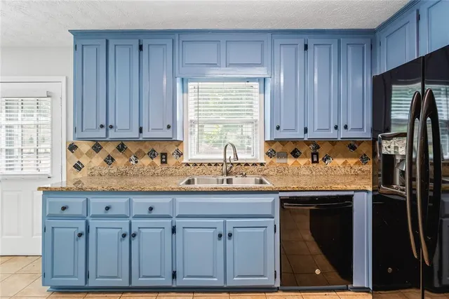 a kitchen with granite countertop a sink cabinets and stainless steel appliances