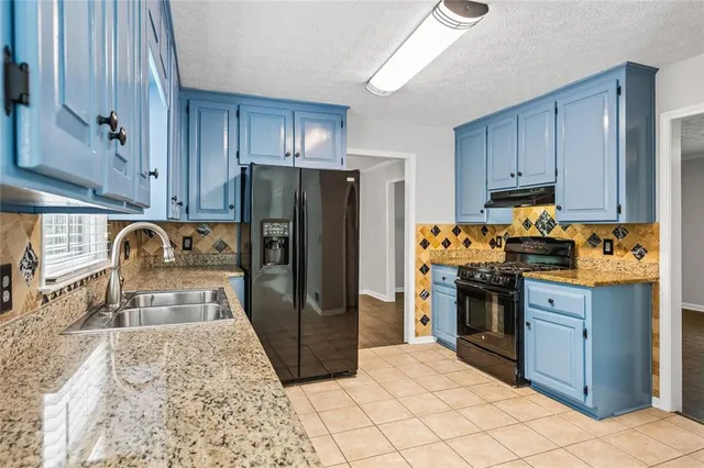 a kitchen with granite countertop a refrigerator stove top oven and sink