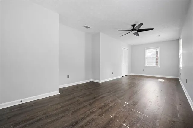a view of empty room with wooden floor and ceiling fan