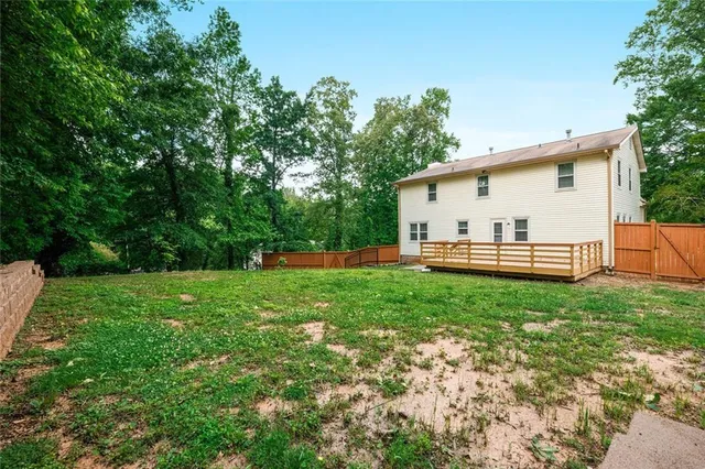 a view of a backyard with table and chairs plants and large tree