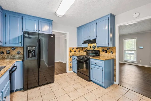 a kitchen with stainless steel appliances granite countertop a refrigerator and a stove