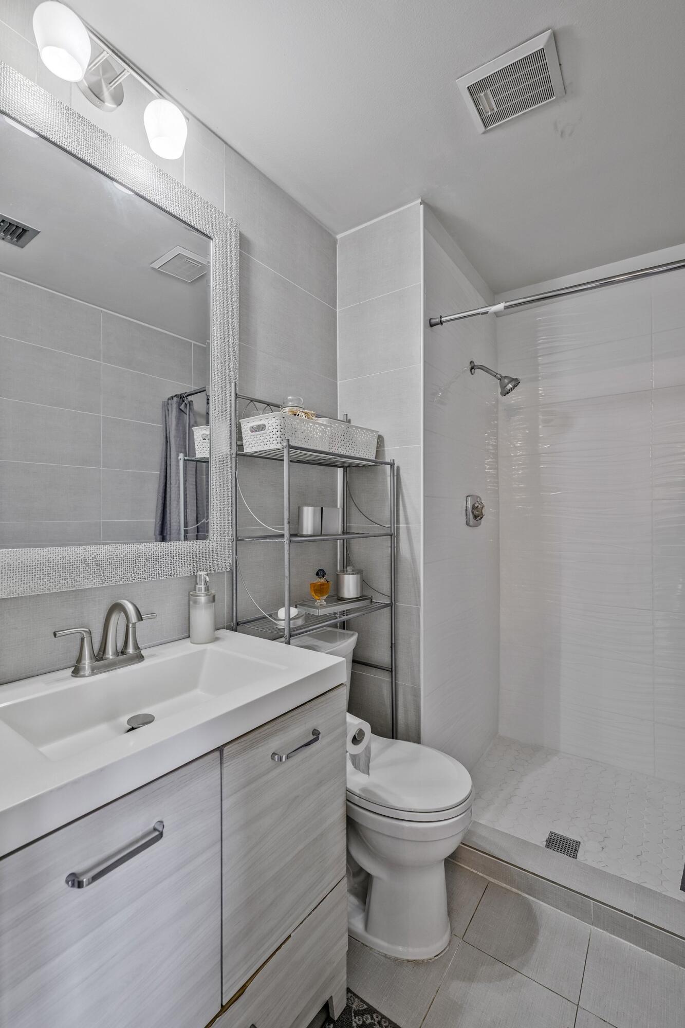 6544 Chasewood Drive, Unit H Jupiter, FL 33458 - Photo 12 of 14 a bathroom with a toilet sink a shower and a mirror