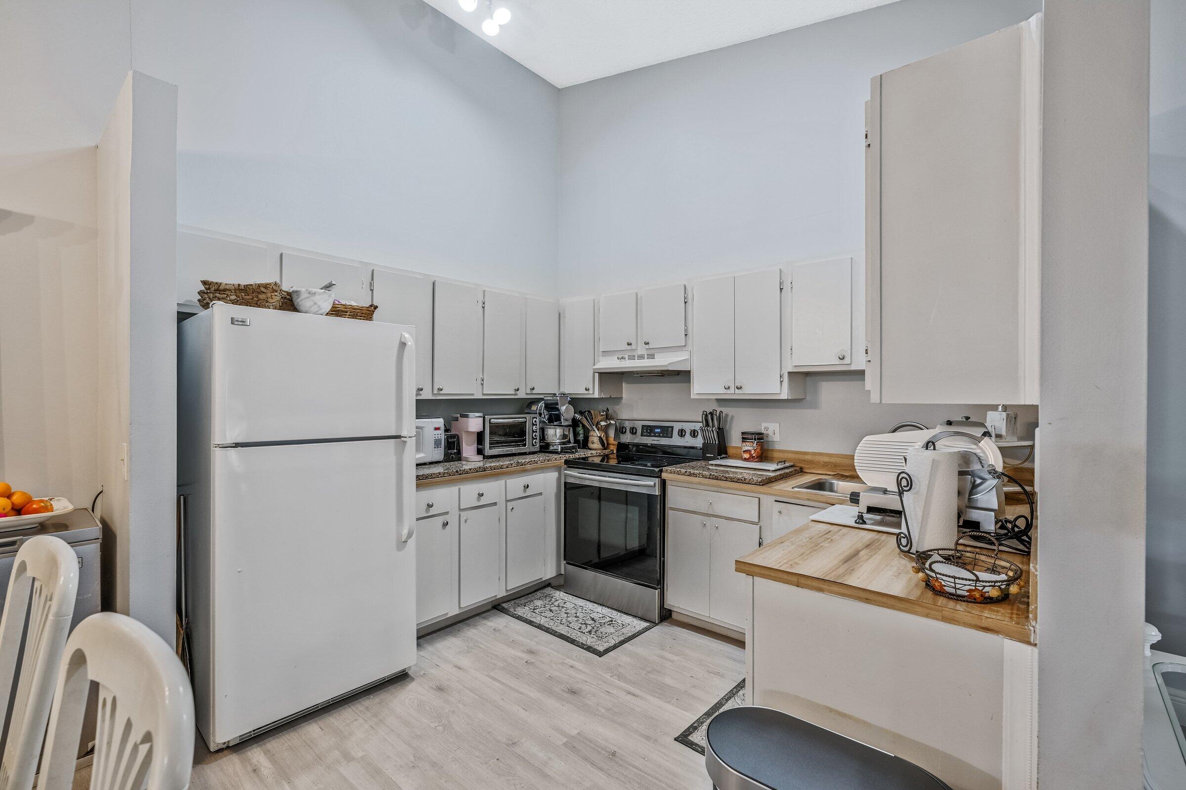 6544 Chasewood Drive, Unit H Jupiter, FL 33458 - Photo 8 of 14 a kitchen with a refrigerator a stove a sink and white cabinets