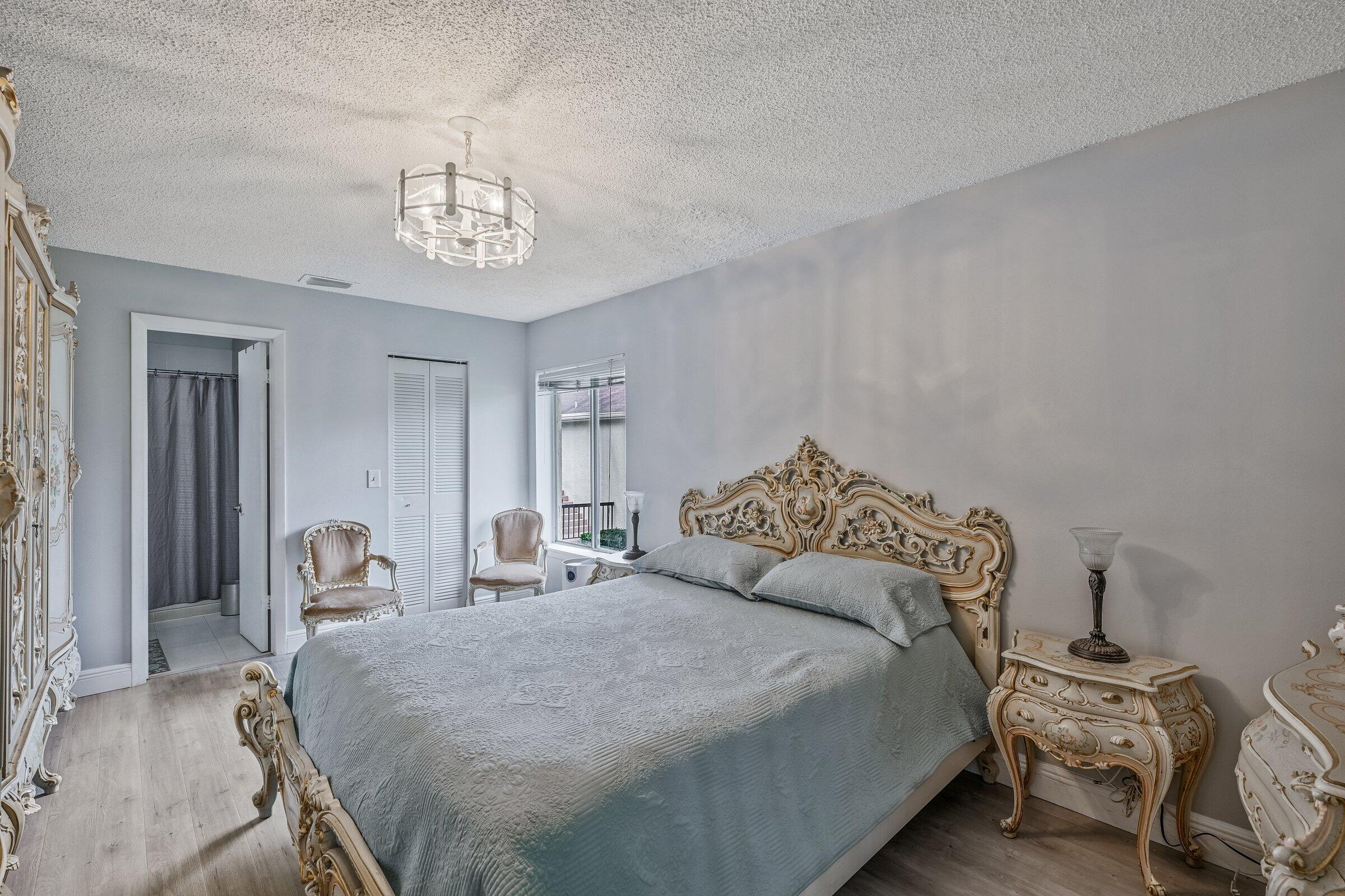 6544 Chasewood Drive, Unit H Jupiter, FL 33458 - Photo 10 of 14 a bedroom with a bed and a chandelier