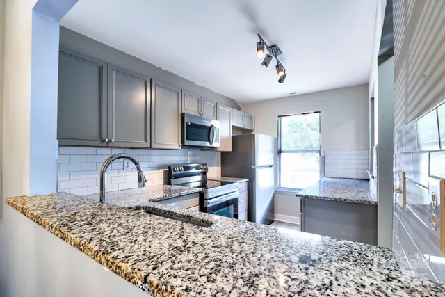 a kitchen with granite countertop a stove a sink and a microwave