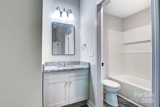 a bathroom with a granite countertop toilet sink and mirror