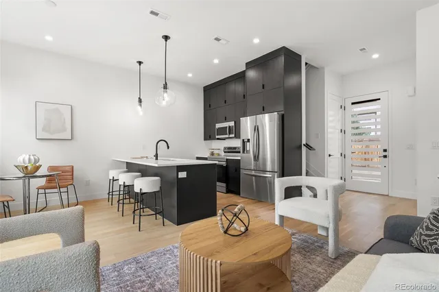 a living room with furniture kitchen and a refrigerator
