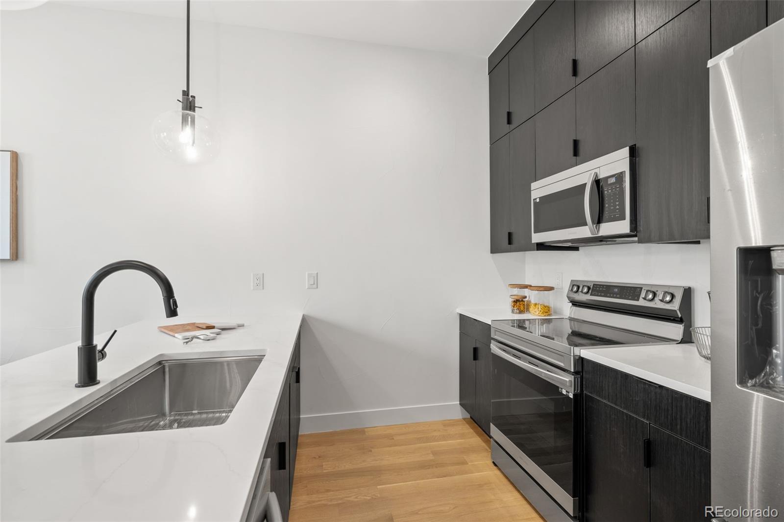 1256 Yates Street Denver, CO 80204 - Photo 11 of 26 a kitchen with stainless steel appliances a stove a sink and a microwave