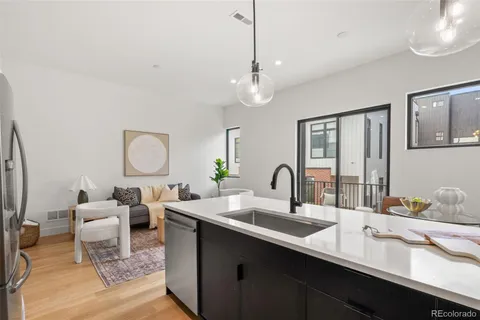 a kitchen with a sink dishwasher a dining table and chairs with wooden floor