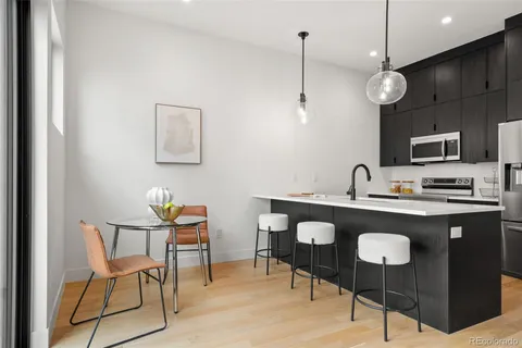 a kitchen with stainless steel appliances granite countertop a sink a stove a refrigerator a dining table with white cabinets and chairs