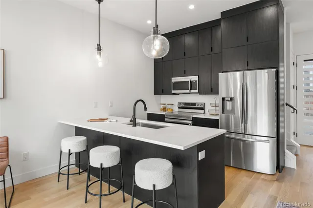 a kitchen with stainless steel appliances a table chairs refrigerator and microwave