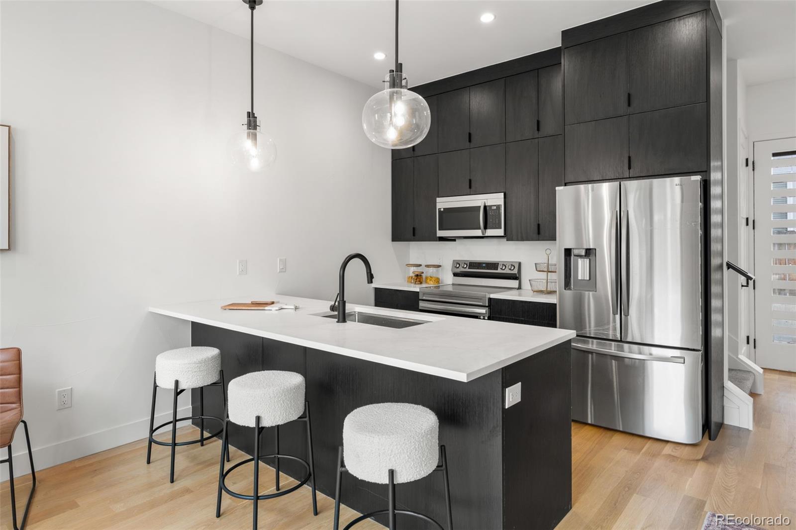 1256 Yates Street Denver, CO 80204 - Photo 8 of 26 a kitchen with stainless steel appliances a table chairs refrigerator and microwave