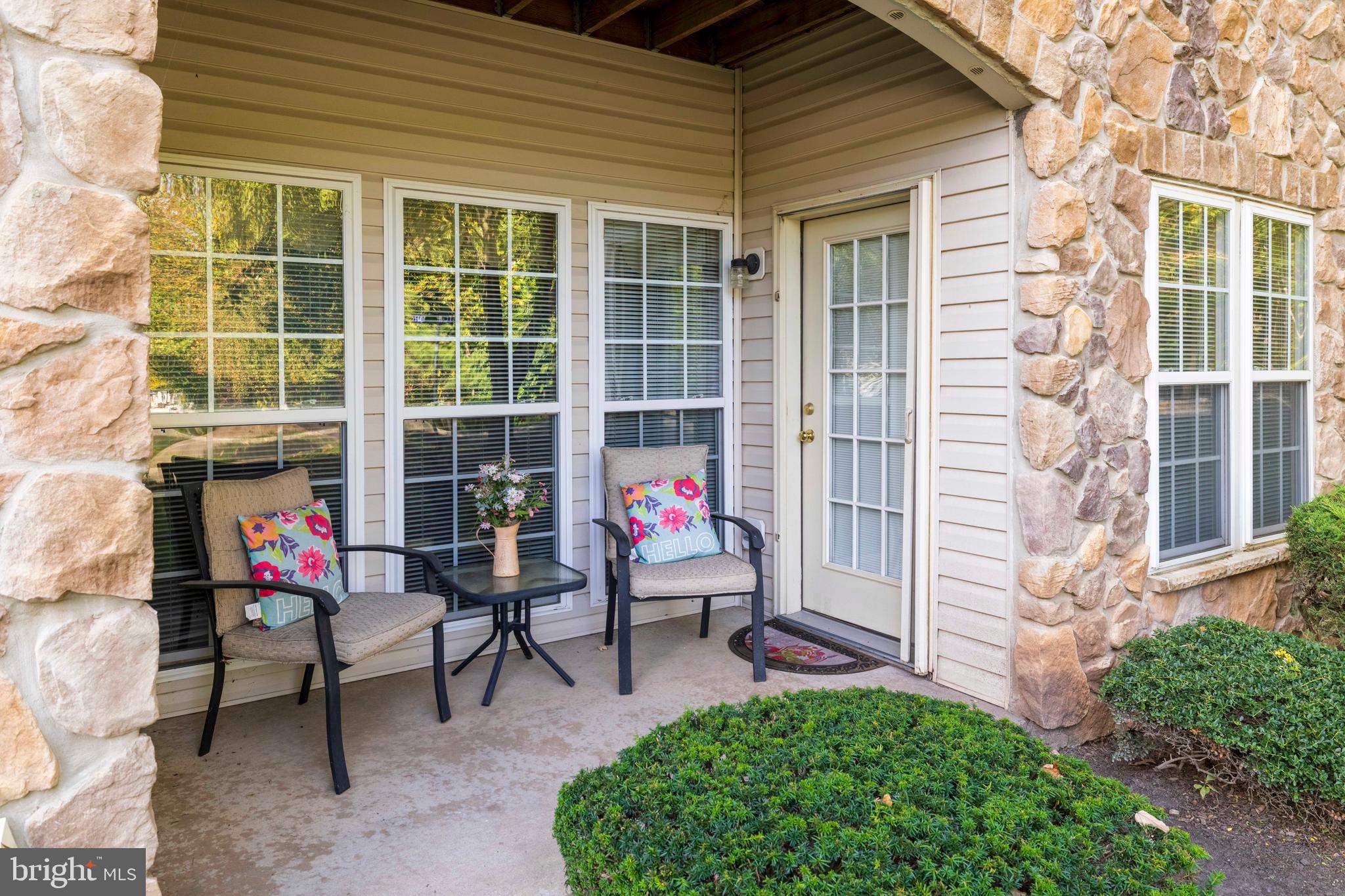 100 Fiddleleaf Lane, Unit 104 Warrington, PA 18976 - Photo 17 of 20 front view of a brick house with a chairs and table in a patio