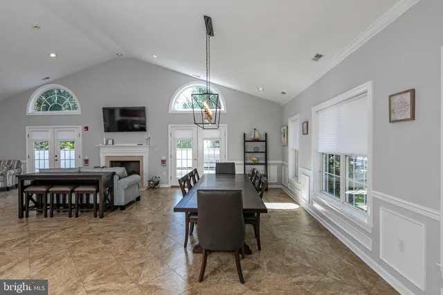 a dining room with wooden floor a chandelier a wooden table and chairs