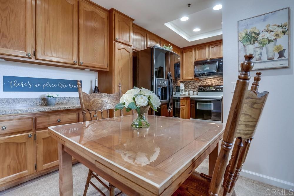 5875 Friars Road, Unit 4404 San Diego, CA 92110 - Photo 7 of 32 a kitchen with stainless steel appliances granite countertop a stove a refrigerator a sink a dining table and chairs with wooden floor