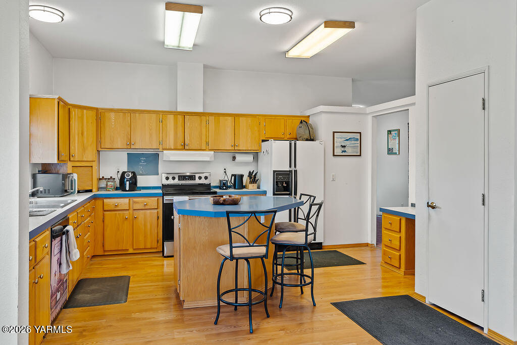 1550 Gibson Road Selah, WA 98942 - Photo 7 of 33 a kitchen with stainless steel appliances granite countertop a stove top oven a sink a dining table and chairs with wooden floor