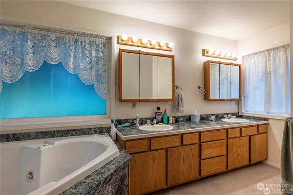 a bathroom with a double vanity sink mirror and bathtub