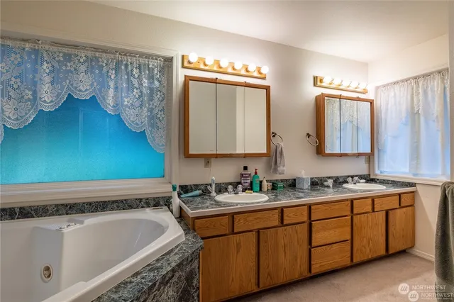 a bathroom with a double vanity sink mirror and bathtub
