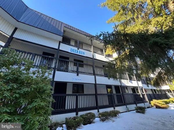 a view of a house with a large tree and wooden fence