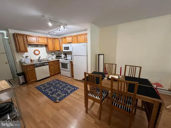 a kitchen with stainless steel appliances granite countertop a stove a refrigerator a sink a dining table and chairs with wooden floor