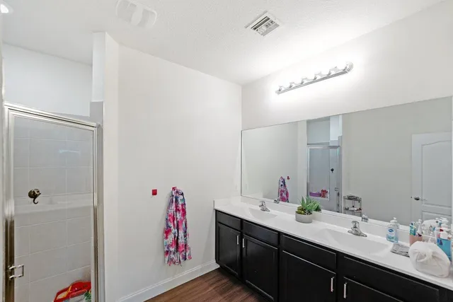 a bathroom with a double vanity sink mirror and shower