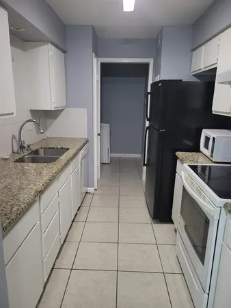 a kitchen with granite countertop a refrigerator and a sink