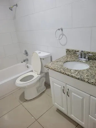 a bathroom with a granite countertop toilet sink and mirror