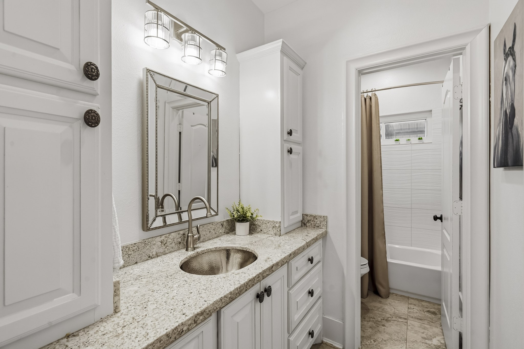 3103 Brundrett Road Wallis, TX 77485 - Photo 31 of 45 : Rich in both sophistication and functionality, this Hollywood Bath is beautifully finished with luxurious granite countertops, a seamless undermount sink, a designer-framed mirror, and an elegant high-neck faucet. The private water closet is tucked away for added comfort and features its own window, inviting natural light and tranquil outdoor views into the space while enhancing its bright, spa-inspired ambiance.