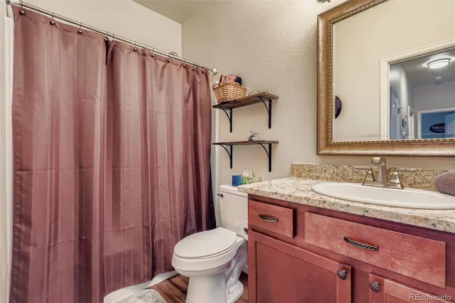 a bathroom with a granite countertop sink toilet and mirror