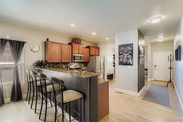 a kitchen with kitchen island granite countertop wooden floor cabinets and stainless steel appliances