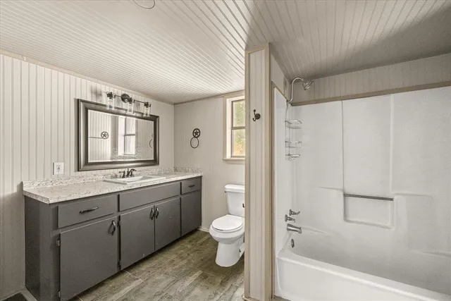 a bathroom with a granite countertop toilet a sink and a bathtub
