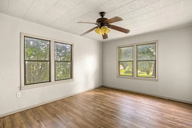 a view of an empty room with wooden floor and a window