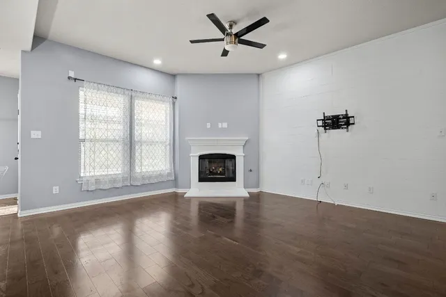 a view of an empty room with wooden floor fireplace and a window