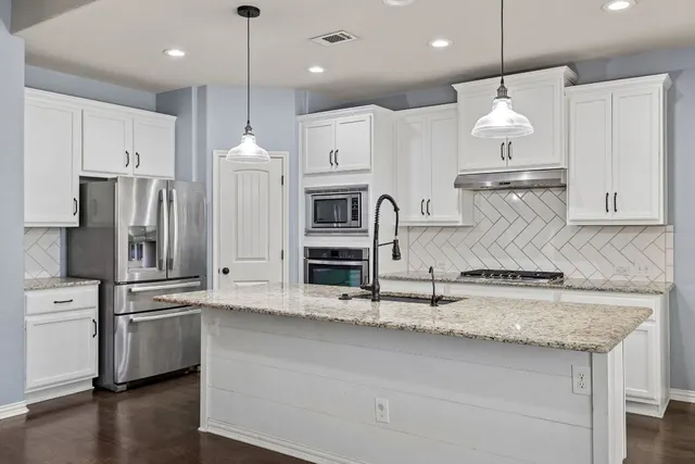 a kitchen with kitchen island a sink stainless steel appliances and cabinets