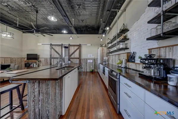 a kitchen with stainless steel appliances a sink a stove and a wooden floors