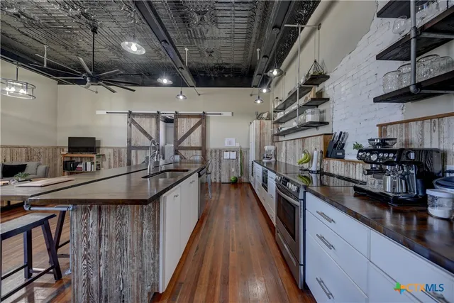 a kitchen with stainless steel appliances a sink a stove and a wooden floors