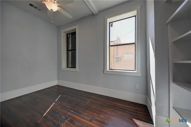 a view of an empty room with wooden floor and a window