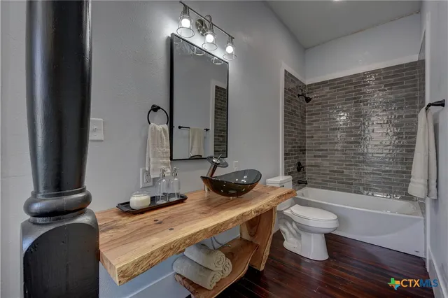 a bathroom with a granite countertop sink a toilet a mirror and shower