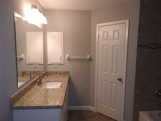 a bathroom with a granite countertop sink and a mirror