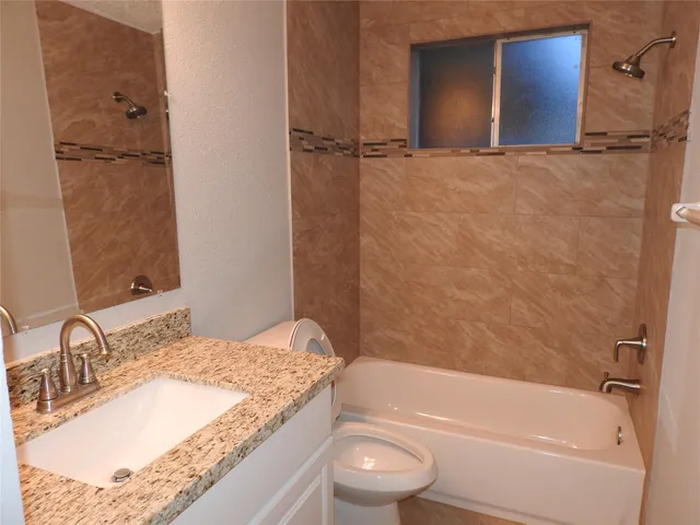 a bathroom with a granite countertop sink toilet and shower