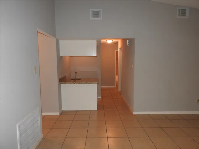 a view of a hallway to an empty room and wooden floor