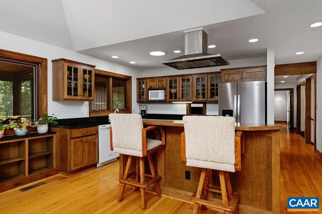 a kitchen with stainless steel appliances kitchen island granite countertop a table chairs and a refrigerator