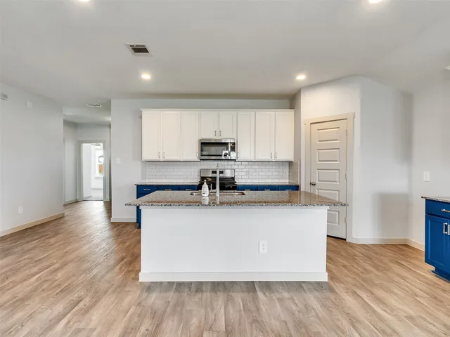 a kitchen with stainless steel appliances granite countertop a sink a stove a microwave and a refrigerator