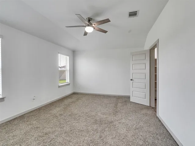 an empty room with windows and fan