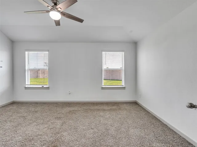 an empty room with windows and ceiling fan