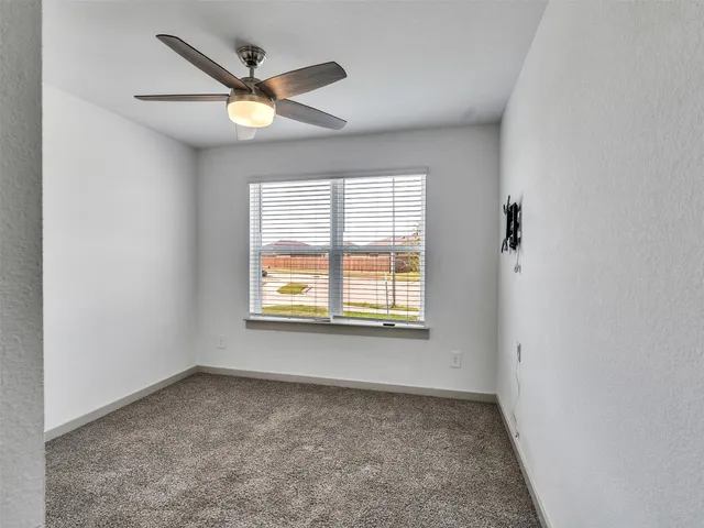 an empty room with a window and a ceiling fan