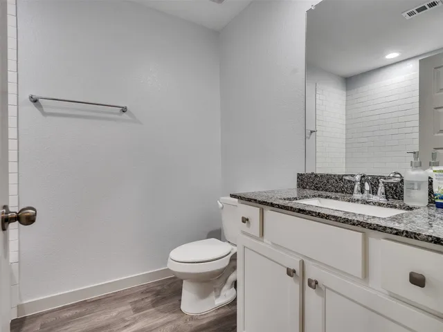 a bathroom with a granite countertop toilet and sink