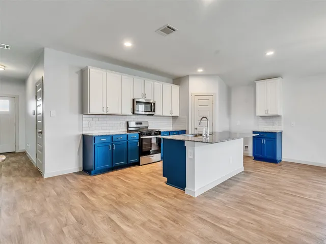 a kitchen with stainless steel appliances kitchen island granite countertop a refrigerator sink and cabinets