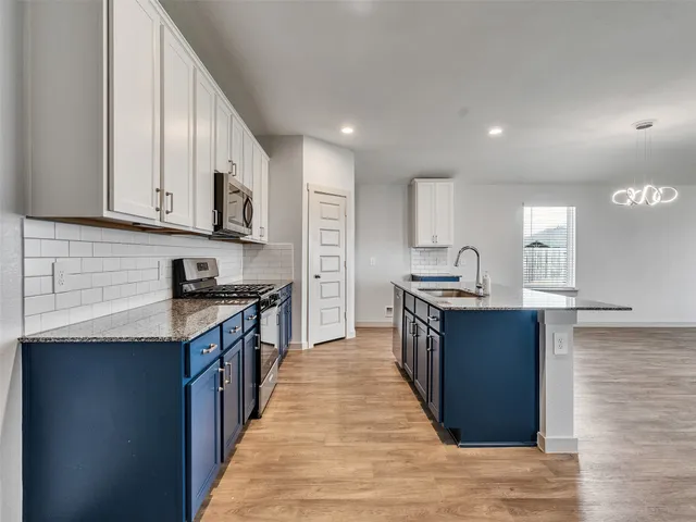 a large kitchen with stainless steel appliances granite countertop a stove a sink dishwasher and a refrigerator