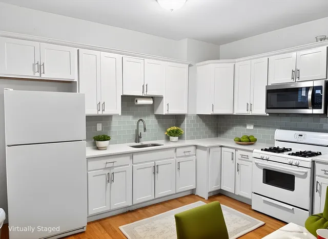 a kitchen with stainless steel appliances a stove a sink and white cabinets